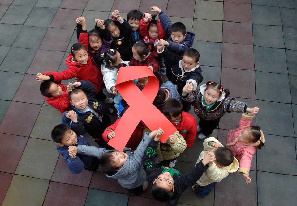 Children pose to raise a red ribbon symbol during an AIDS awareness activity at a kindergarten in Hefei